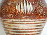 a brown and white vase sitting on a white surface