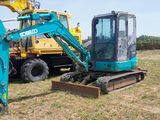 two excavators that are sitting in the grass