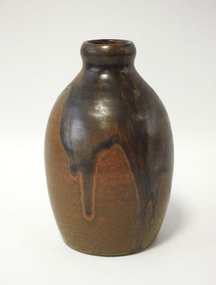 un vase marron posé sur une surface blanche, avec un fond blanc