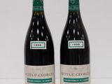 two bottles of red wine sitting next to each other on a table