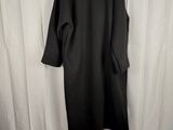 a black coat hanging on a white curtain next to a bed
