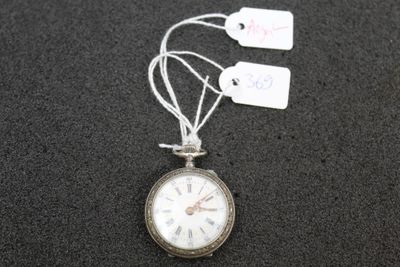 a silver pocket watch with tags attached to it