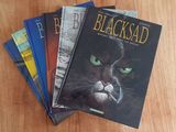 several books on a wooden table with a black cat on the cover