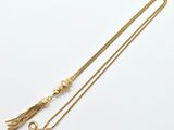 un collier en or orné d'un pompon et d'une chaîne en or