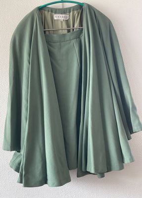 a close up of a green jacket on a hanger on a wall