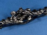 a silver brooch with a crown on it on a blue surface
