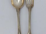 two silver spoons and a fork on a white surface