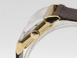 a close up of a watch on a clear surface with a brown strap