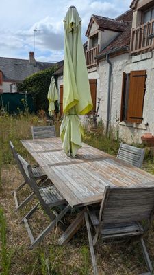 une table en bois avec des chaises et des parasols dans le jardin