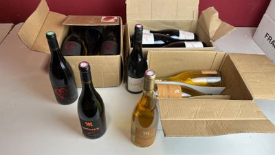 Plusieurs bouteilles de vin sont posées dans une boîte en carton sur une table