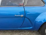 a small blue car parked on the side of the road