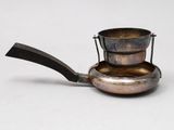 a small metal pot with a handle on a white surface