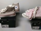 deux paires de Converse roses et blanches posées sur une boîte noire