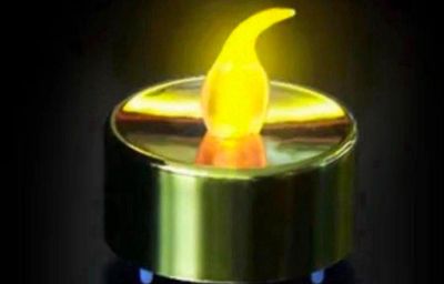 a yellow candle that is lit in the dark