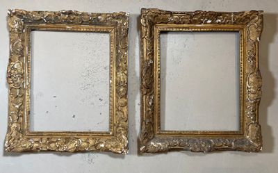 une paire de cadres dorés ouvragés accrochés à un mur blanc
