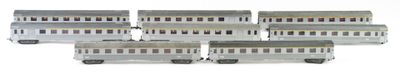 six silver train cars are lined up on a white surface