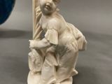 a small figurine of a boy sitting on a rock