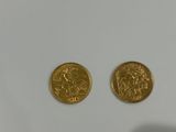 a pair of gold coins sitting on top of a white surface