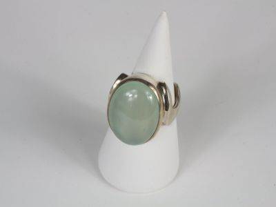 a close up of a ring with a green stone on a white cone