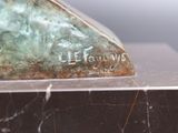a bronze sculpture of a bird sitting on top of a marble block