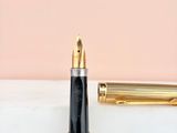 a gold fountain pen sitting on top of a marble counter