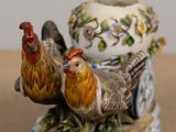 a figurine of two chickens sitting on top of a vase