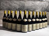 bottles of wine are lined up on a table in front of a stone wall