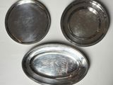 trois plateaux en argent posés sur une table blanche