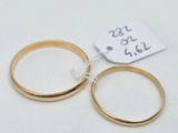 two gold wedding rings on a white surface with a price tag