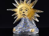 a glass figurine of a sun with a face on it
