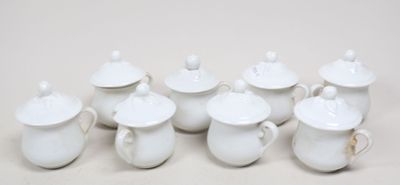 sept théières blanches avec leurs couvercles, posées sur une table blanche