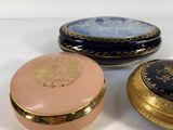 three small round boxes with gold and blue designs are sitting on a white surface
