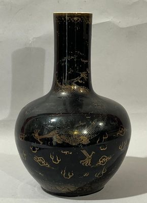 un vase noir orné de motifs dorés sur fond blanc