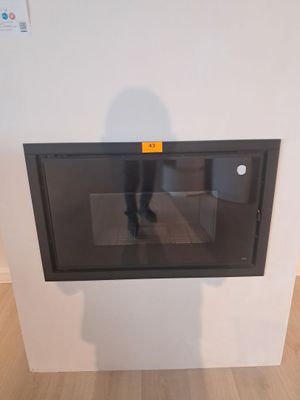 une personne debout devant un micro-ondes fixé au mur