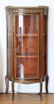 a glass display cabinet with a wooden shelf in the corner