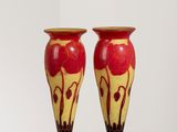 une paire de vases rouges et jaunes posés sur un socle blanc