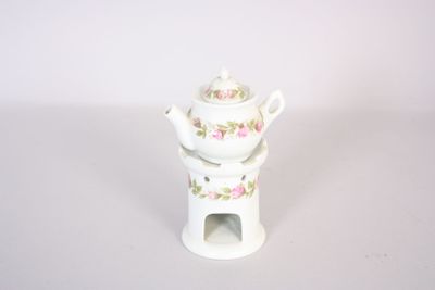 a small white teapot with a pink rose design on it