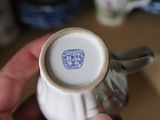 a person holding a white vase with a blue seal on it