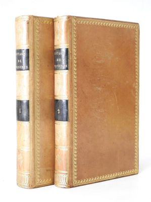 un vieux livre posé sur une table blanche à côté d'un livre brun