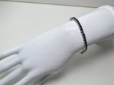 bracelet orné de diamants noirs et blancs, présenté sur la main d'un mannequin