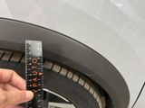 a person measuring the width of a tire with a ruler