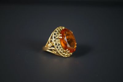 une bague en or sertie d'une pierre orange entourée de filigrane
