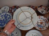 a person holding a plate in front of a table full of plates