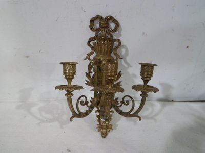 une applique murale dorée avec trois bougies dessus