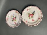 two plates with floral designs on them sitting on a table