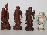 Trois figurines asiatiques sont posées à côté d'un vase sur une table