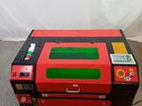 une machine laser rouge et noire posée sur un sol en béton