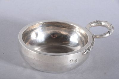 un petit bol en argent avec une anse sur une table