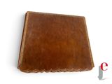 brown leather book with scalloped edges on a white surface