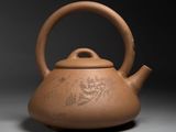 an old brown teapot with a bird design on it